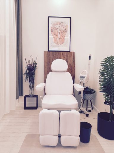 Ein heller Raum mit einem weißen Behandlungsstuhl und Pflanzen im Hintergrund.