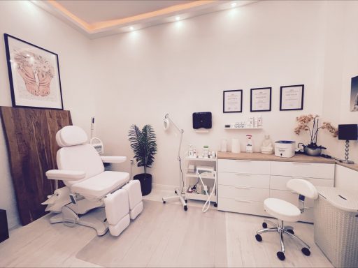 Behandlungsraum mit einem weißen Behandlungstisch, Stühlen und medizinischen Geräten.