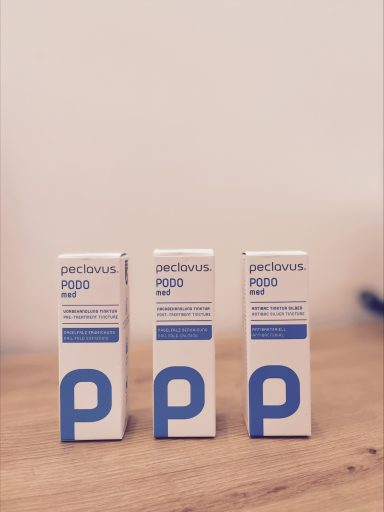 Drei Produktverpackungen mit blauen und weißen Designs auf einem Holztisch.